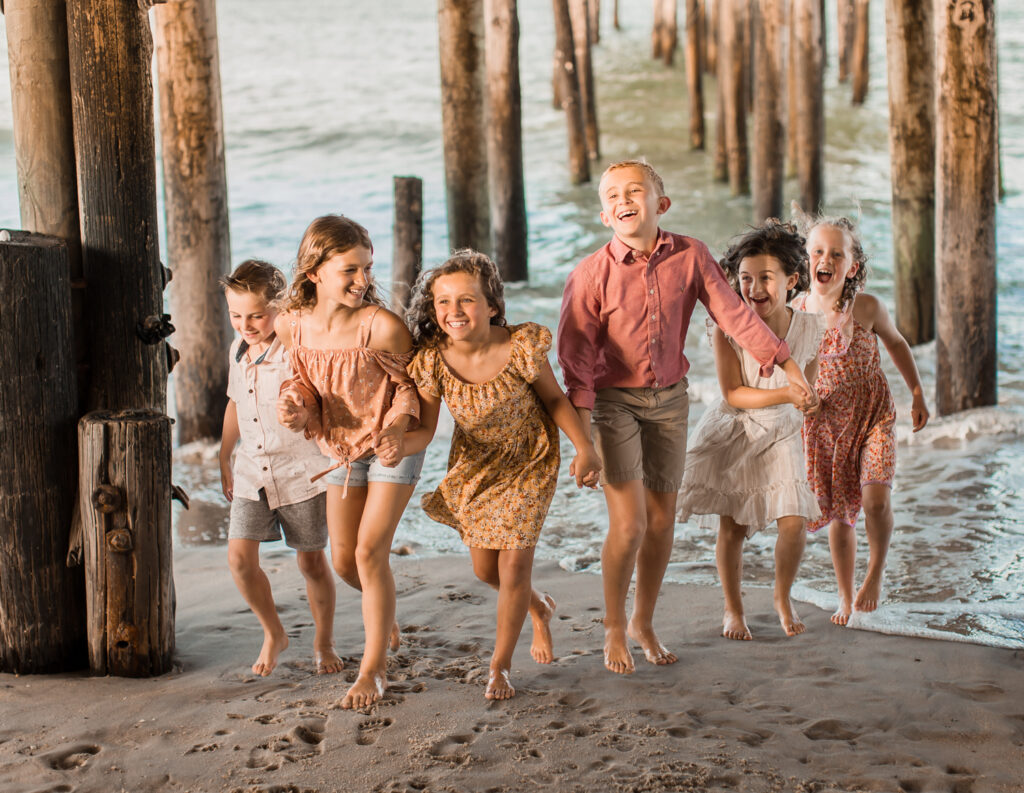Kids running on beach under pier