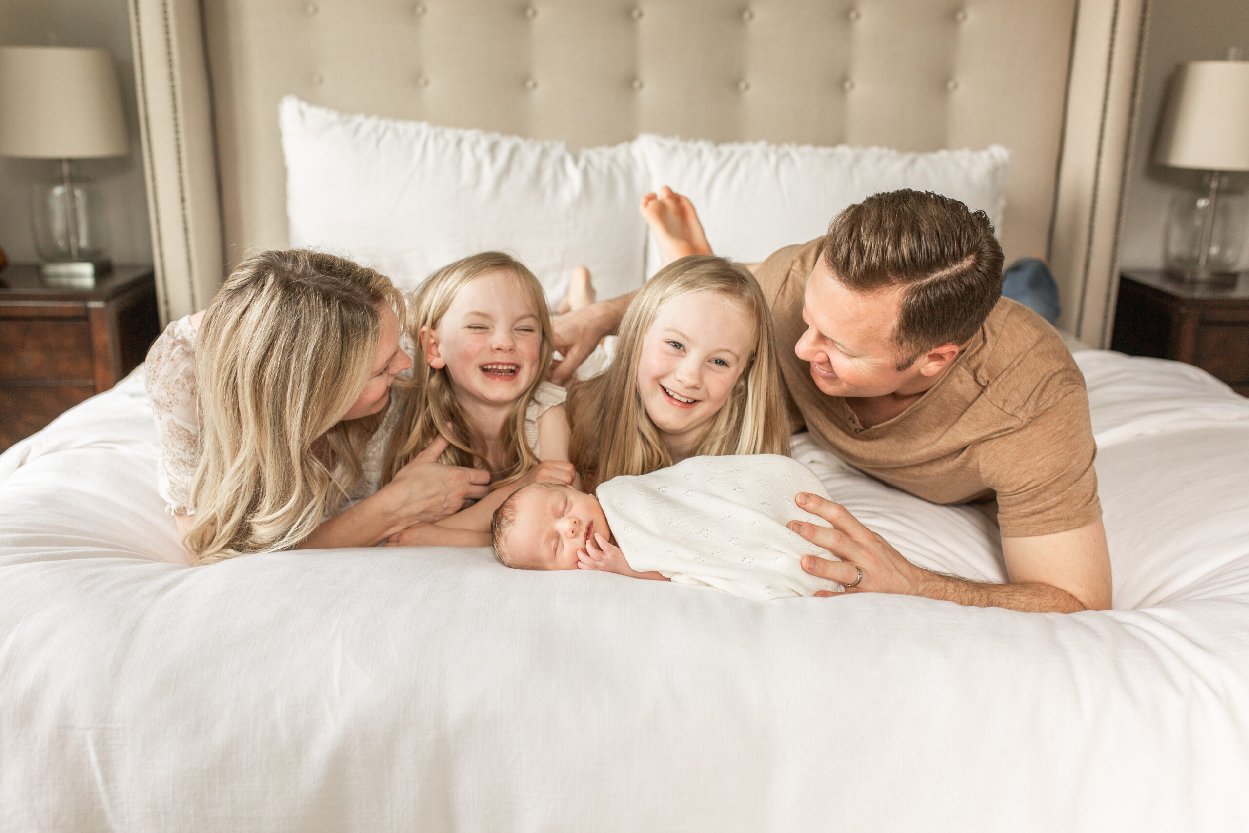 Family laughing with newborn baby and 2 sisters