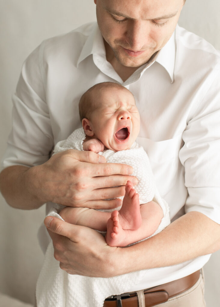 dad holding yawning newborn baby