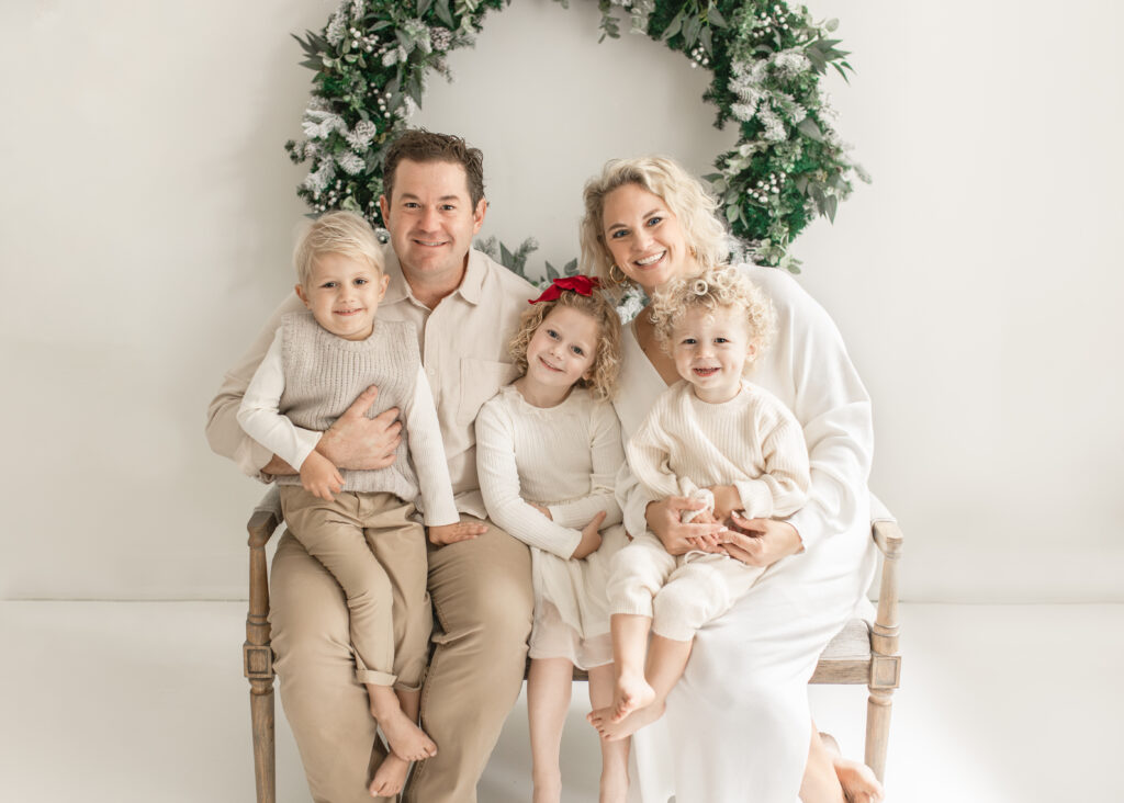 family of five in front of christmas wreath